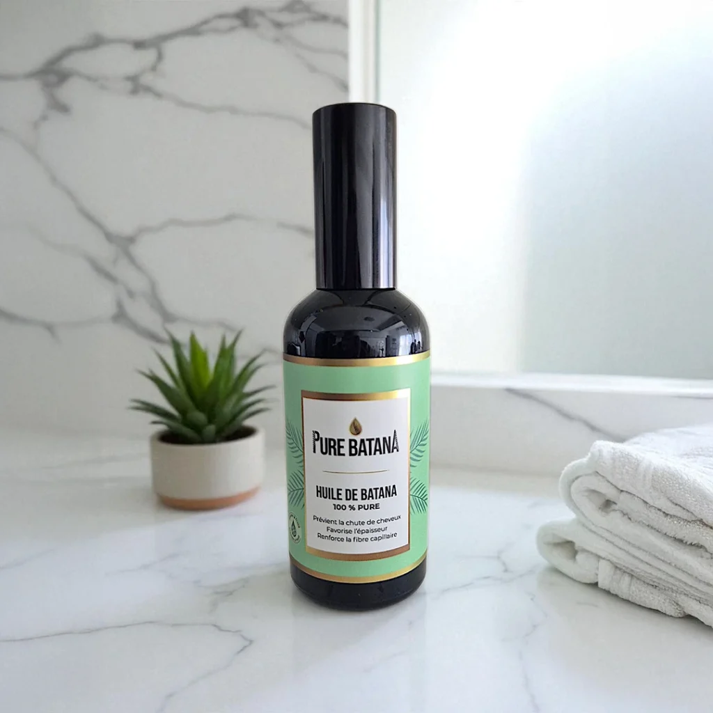 Bouteille d'huile de Batana Pure Batana posée dans une salle de bain, huile capillaire naturelle pour cheveux crépus et bouclés.